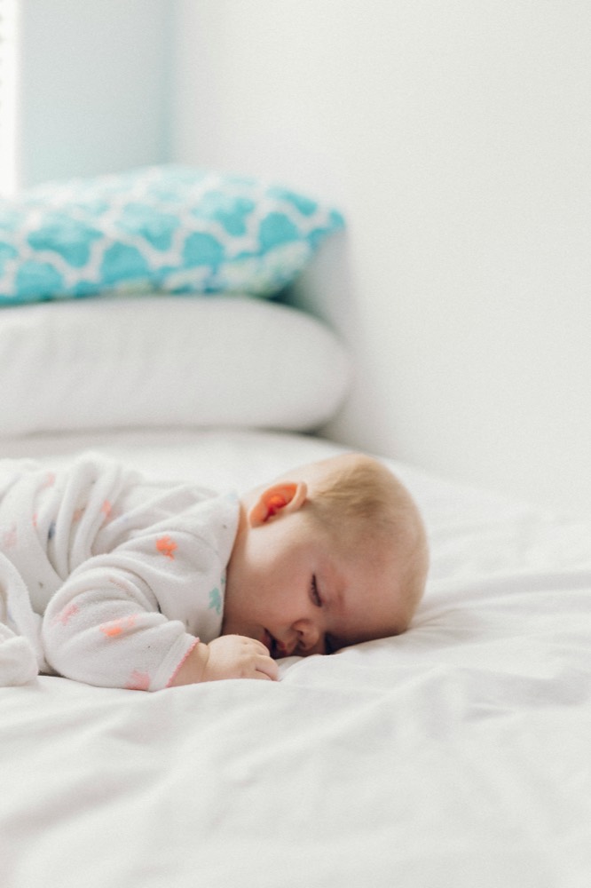 A baby asleep on a white bed