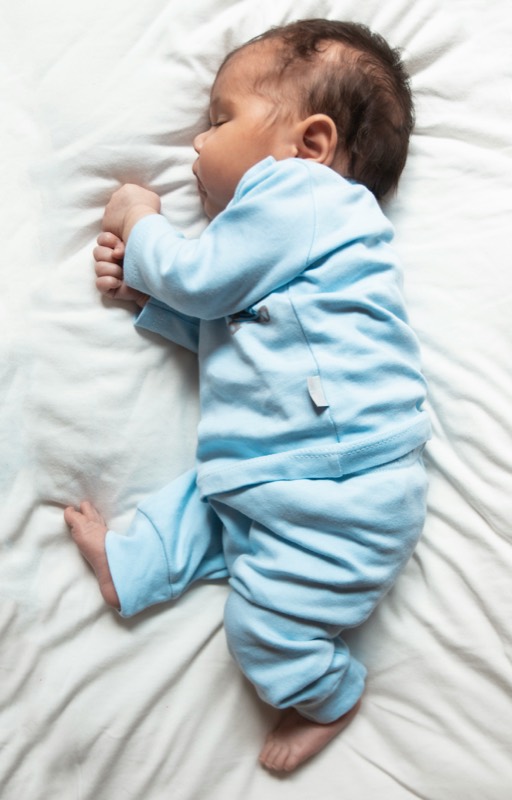 A newborn asleep in a blue outfit